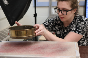 Hannah Elston preparing the model by sprinkling sand on the surface of the clay.