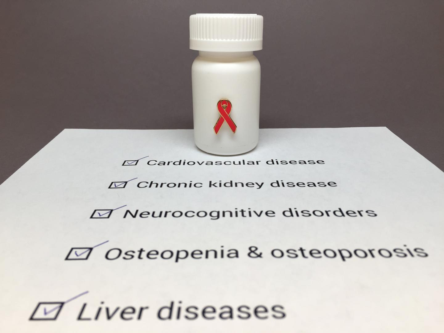 Pill Bottle with a Red HIV Awareness Ribbon Sitting on a Piece of Paper Listing of HIV Comorbidities