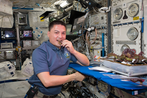 NASA astronaut Kjell Lindgren takes a bite of a lettuce plant