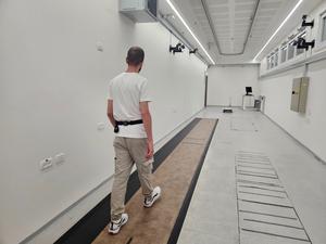 A person walking in a state-of-the-art gait lab, with a wearable sensor positioned on his lower back.