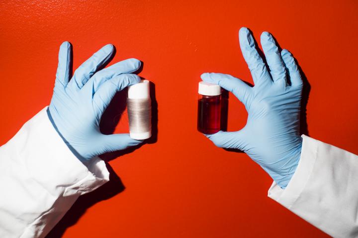 Researcher Holding Spools of Thread Created From Squid Pigment