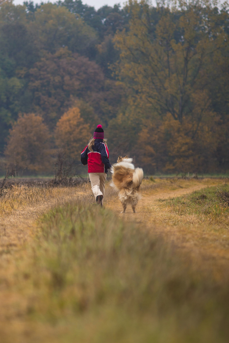 A girl running alongside her dog.