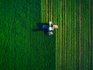 Tractor mowing green field, aerial view