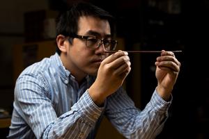 Materials scientist Xiao Li examines a wire created through solid phase processing.