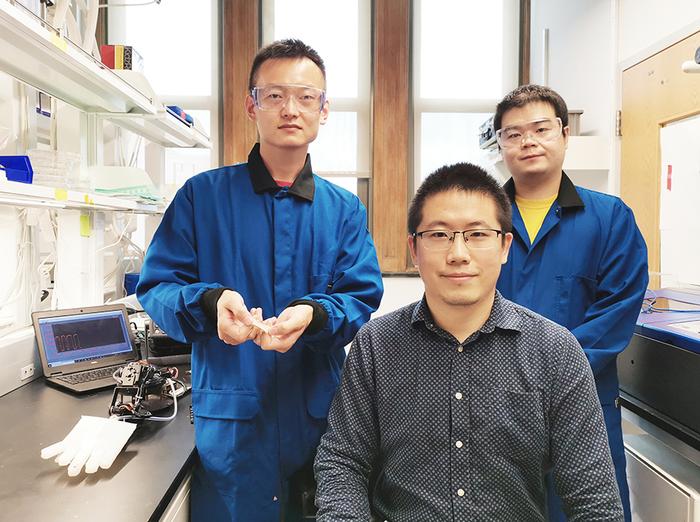 Sihong Wong with PhD students displaying sensor and soft robotic hand