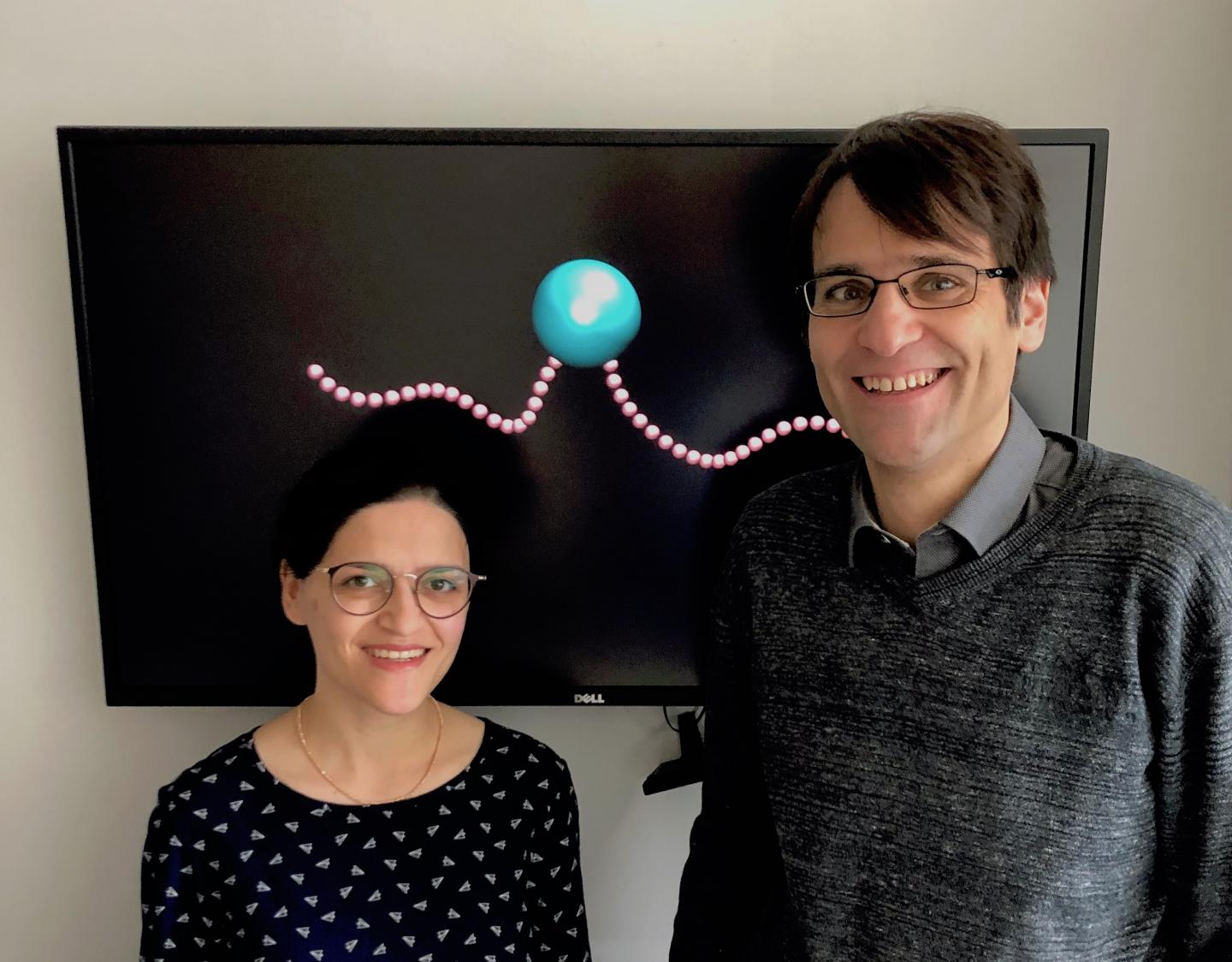 Researchers in front of image of bacterium on a black background