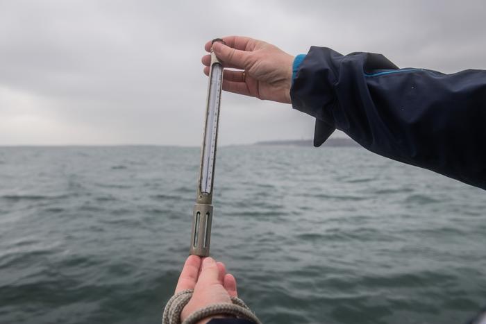 Karen Wiltshire holds a thermometer on the research vessel Aade