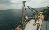 Crew on a Ship Using a Crane to Deploy a Receiver in the Ocean