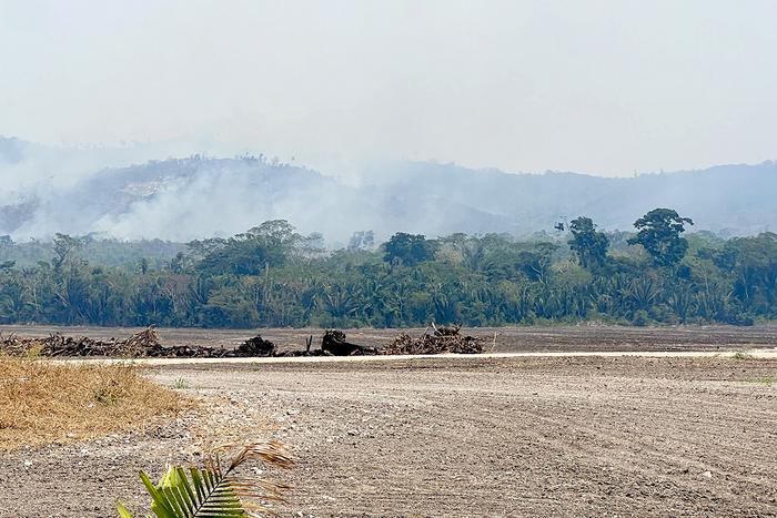 Wildfires and smoke surround the excavation site.