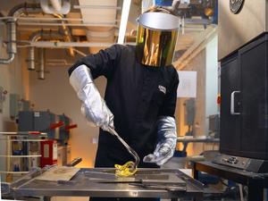 A researcher molds a piece of glass after removing it from a forge