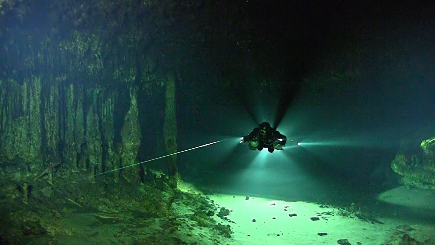 Diver uses a Flashlight to Navigate an Underwater Cave