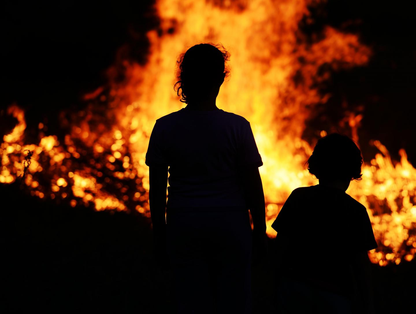 Children Standing in Front of a Fire