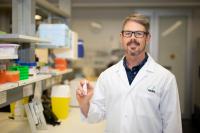 Associate Professor Nathan Bartlett holds Mockup of Immune Boosting Nasal Spray in HMRI Labs