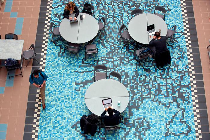 Students work on laptops above “Gene Pool,” a tile mosaic by Andrew Leicester inside the Molecular Biology Building at Iowa State University.
