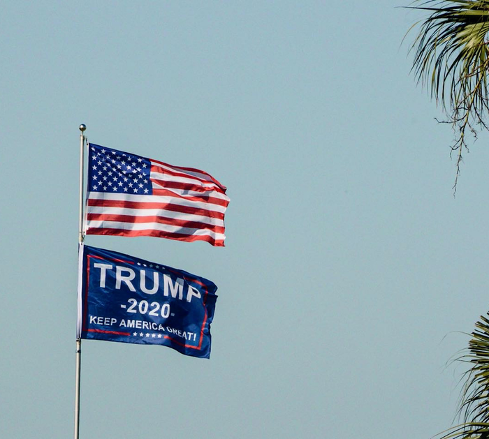 The flag of the United States of America above a flag of Donald Trump’s 2020 presidential bid.