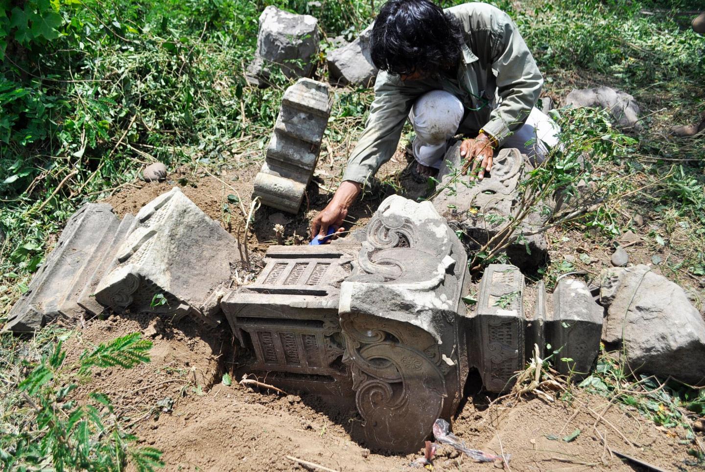 Project staff member recording broken medieval carved stone grave marker.