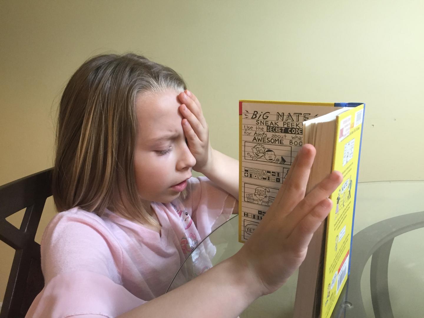Child Covering Eye while Looking at Book