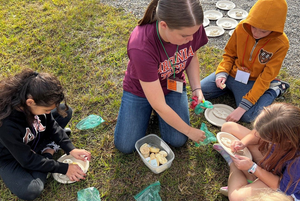 Graduate student Brogan Holcombe (at top center) leads Wildlife Viewing Club participants in an activity that involved making clay molds of wildlife footprints.