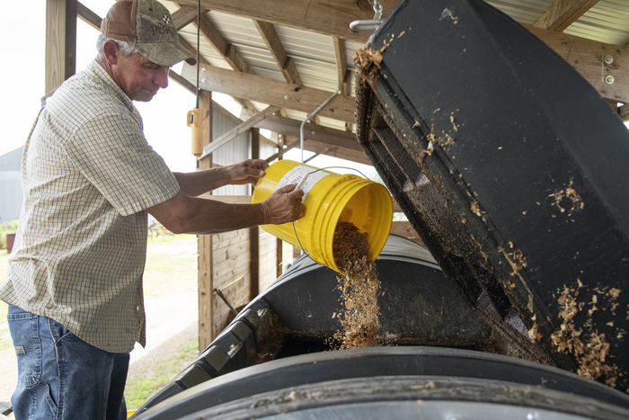 A man dumping food waste into a composter.