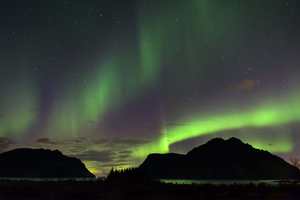Green Auroras (also called the Northern Lights) flash above a mountain range