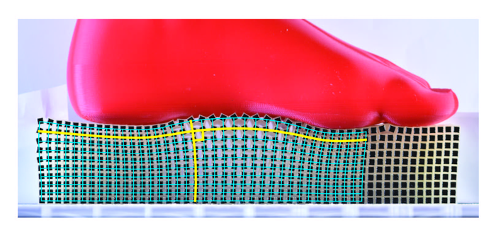 The “Rotating Squares” metamaterial deforms conformally, with the blue grid of right angles remaining at right angles after deformation by a foot shaped object.