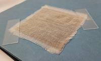 Graphene Laminate with Active Barrier Layer behind a Light Fiber-Based Fabric