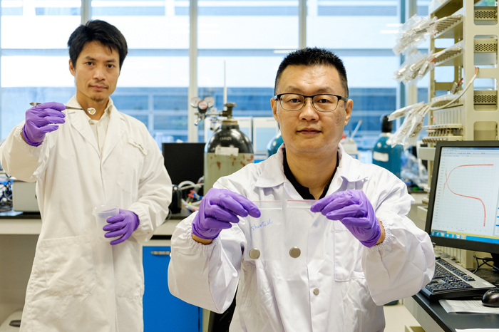 Prof Jason Xu (right) holding a short-circuited battery in his right hand and the new technology in his left