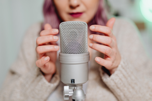 A woman touching a microphone to trigger the Autonomous Sensory Meridian Response (ASMR)