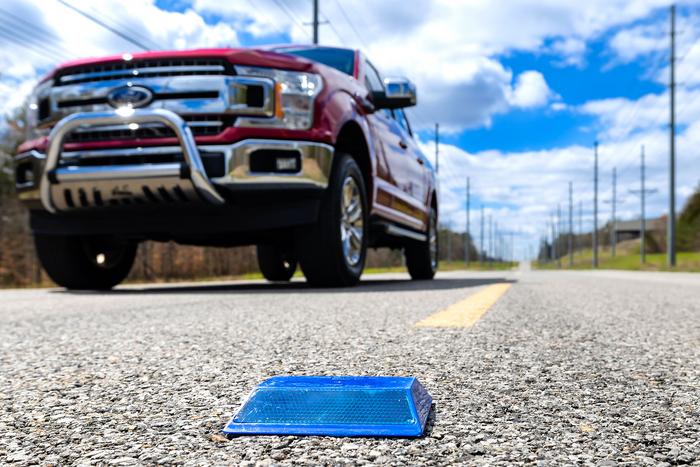 Truck driving past raised sensor-equipped raised pavement marker