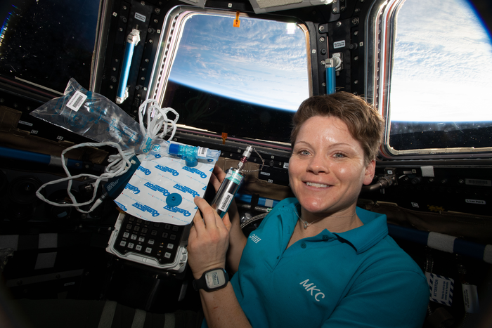 Astonaut Anne McClain holding biomedical gear for MARROW