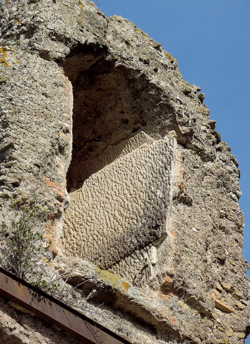 A field photograph showing travertine crystal growth ripples on the vertical side wall of the Anio Novus aqueduct at Empiglione Bridge.