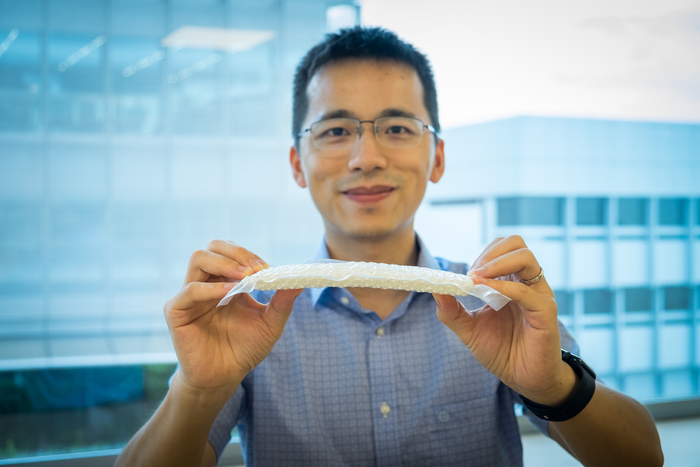 NTU Asst Prof Wang Yifan holding the stiffened nylon chain mail in a vacuum-packed envelope