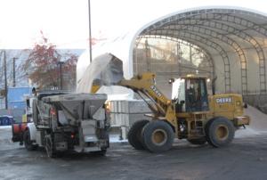 A loader pours salt into the back of a truck