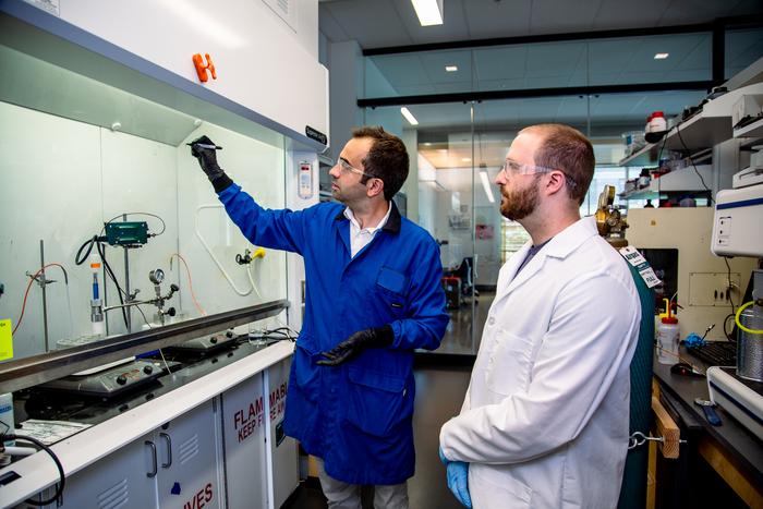 Scott Svadlenak, right, and Kostas Goulas discuss possible reaction mechanisms for the PVC to waxes process. Photo by Johanna Carson.