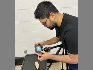 A man takes images of a sweet potato with a camera in a laboratory setting