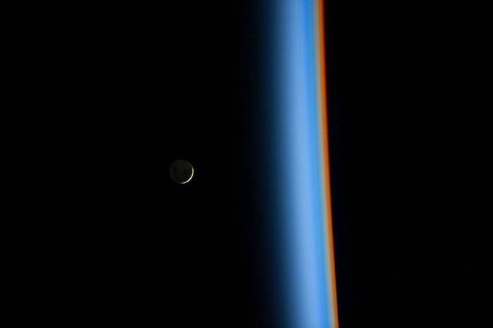 Crescent moon rising above the cusp of the Earth’s atmosphere