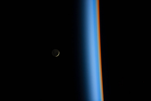Crescent moon rising above the cusp of the Earth’s atmosphere