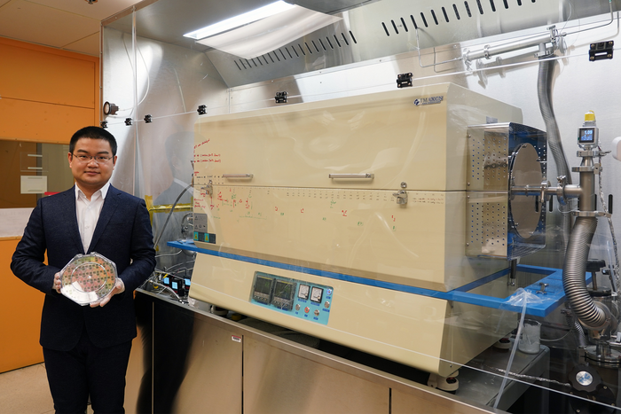 Graduate student Jiadi Zhu holding an 8-inch CMOS wafer with molybdenum disulfide thin film.