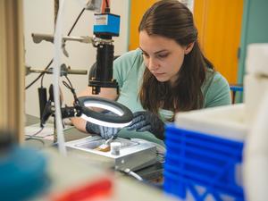 A researcher examines a water droplet under a lamp in a lab