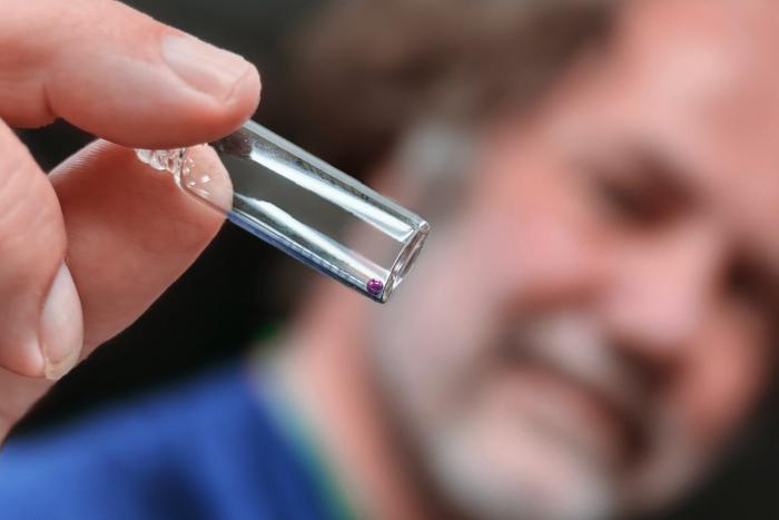 Scientist holds a vial with a glass bead