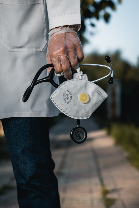 A doctor holds a face mask and stethoscope.