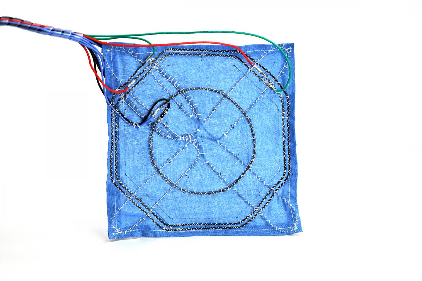 Top-down image of a robotic fabric with integrated actuation, variable stiffness, and sensing fibers.