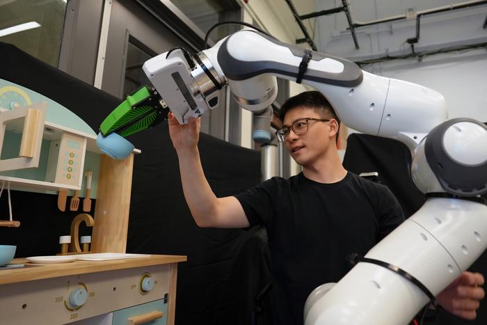 Graduate student Felix Yanwei Wang nudges a robotic arm