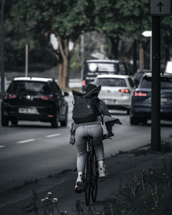 Man in Black Jacket and Black Backpack Riding Bicycle on Road