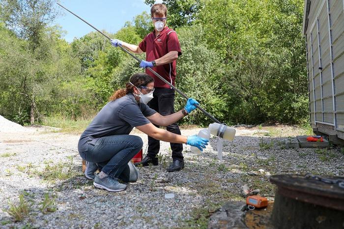 Amy Pruden (kneeling) and Peter Vikesland examine a wastewater sample.