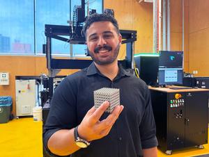 PhD candidate Jordan Noronha holding a sample of the new titanium lattice structure 3D printed in cube form. Credit: RMIT.