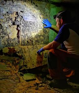 A termite infestation specialist inspects the damages caused by termites on a house wall.