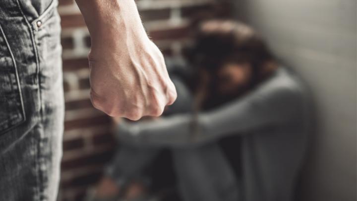 Man Stands with Fist Clenched, While a Woman Cowers in the Corner