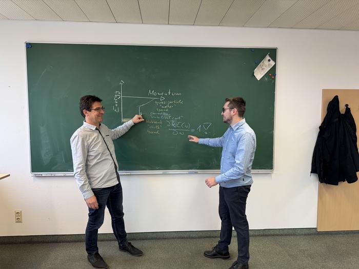 Two researchers in front of the blackboard