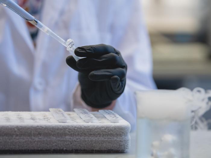 A researcher in a lab coat pipetting